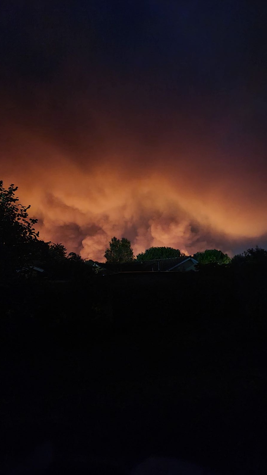 Ciel nocturne embrasé, sombre et oppressant au-dessus d'un quartier silencieux