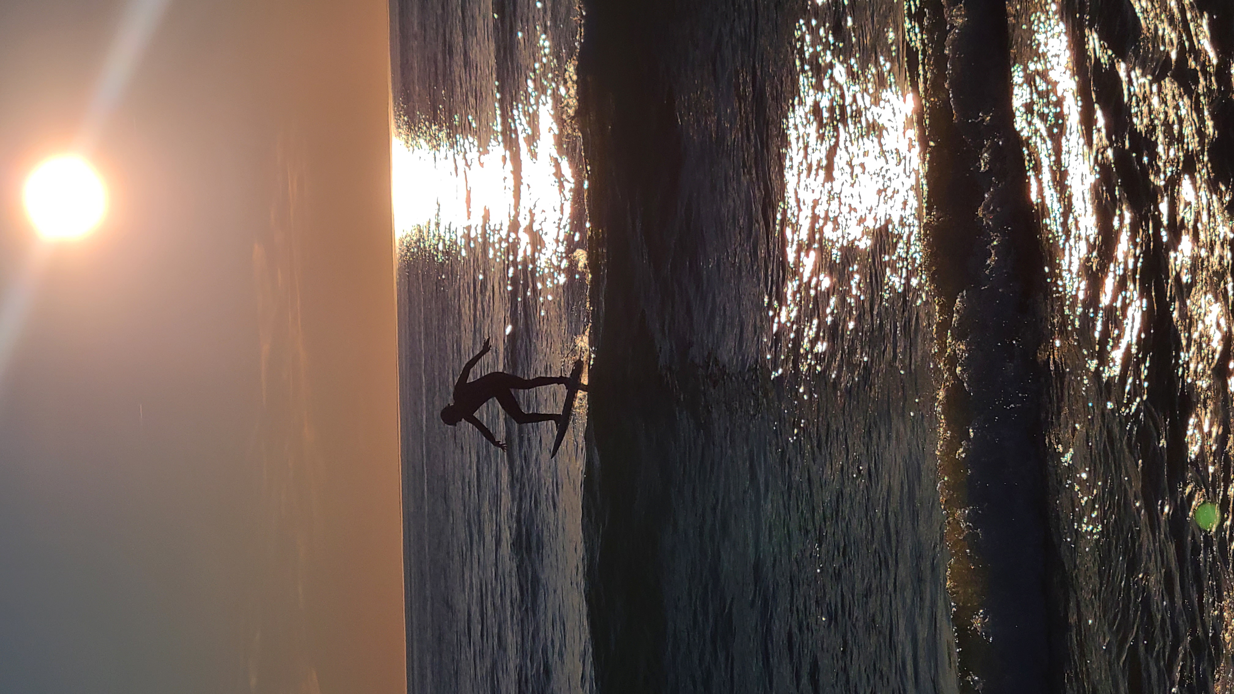 Une silhouette en équilibre sur une planche, glissant sur l'eau à contre-jour du soleil couchant