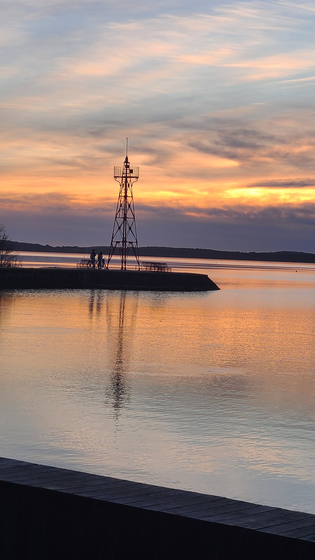 Un phare se détachant sur un ciel de coucher de soleil, au bord de l'eau